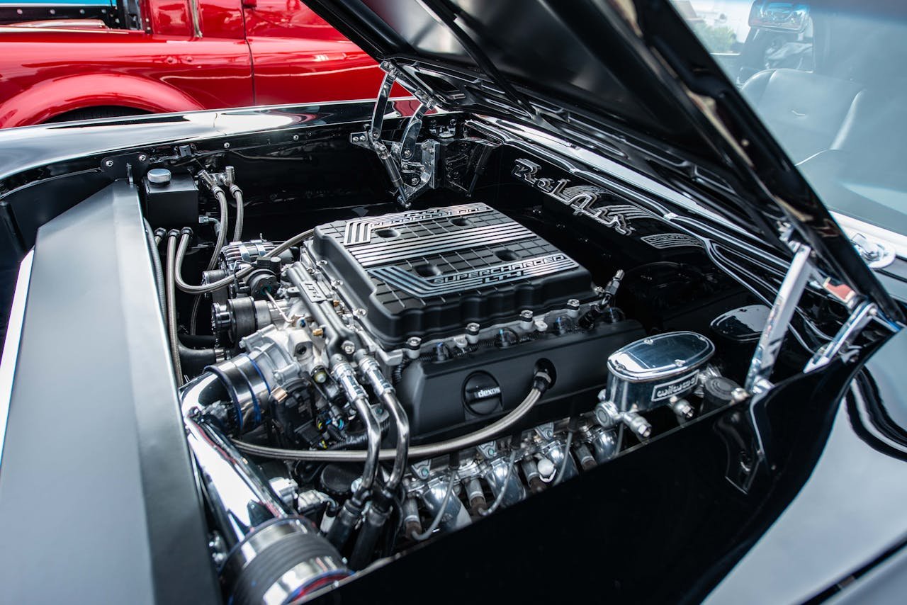 Close-up of a classic car engine, showcasing shiny chrome and metallic details.